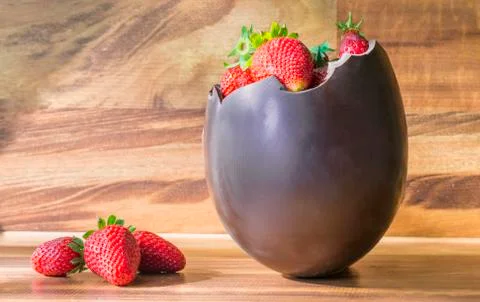 Chocolate Easter egg with the top broken off filled with strawberry Stock Photos