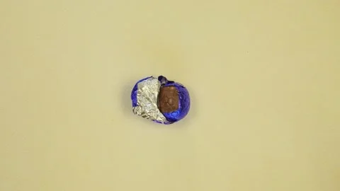 Chocolate Easter egg unwrapping sparkling shiny blue foil top view, wrapped Stock Footage 233184457