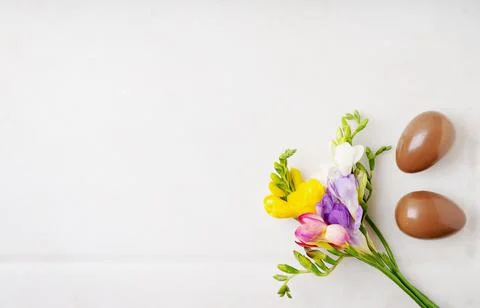 Chocolate Easter eggs and Fresh colorful wildflowers over white background. H Stock Photos