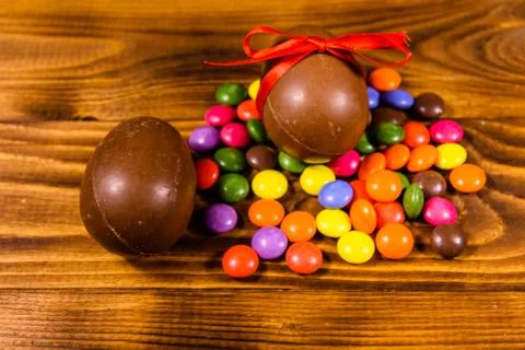 Chocolate easter eggs and multicolored candies on wooden table Stock Photos