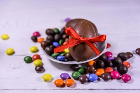 Chocolate easter eggs and multicolored candies on wooden table Stock Photos