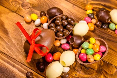 Chocolate easter eggs and multicolored candies on wooden table. Top view Foto stock