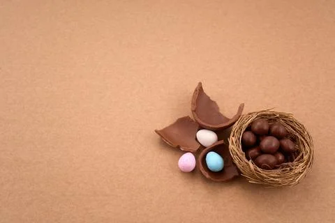 Chocolate easter eggs and nest with candy on brown background Stock Photos