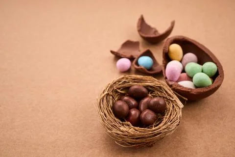 Chocolate easter eggs and nest with candy on brown background Stock Photos