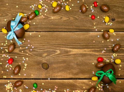 Chocolate Easter eggs and sweets on wooden background. Top view. Space foe te Stock Photos