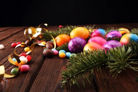 Chocolate Easter eggs, colorful eggs and sweets on wooden background Stock Photos