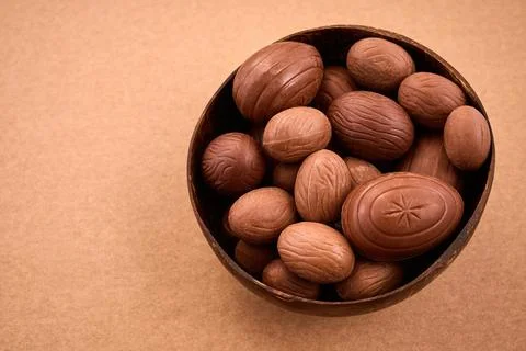 Chocolate easter eggs filling coconut bowl on brown background Stock Photos