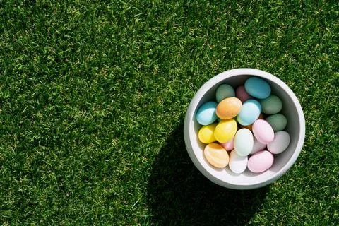 Chocolate Easter eggs glazed with pastel coloring in a bowl over green grass Stock Photos