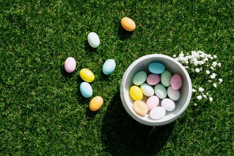 Chocolate Easter eggs glazed with pastel coloring in a bowl  and over green g Stock Photos