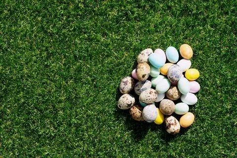 Chocolate Easter eggs glazed with pastel coloring and quail eggs over green g Stock Photos