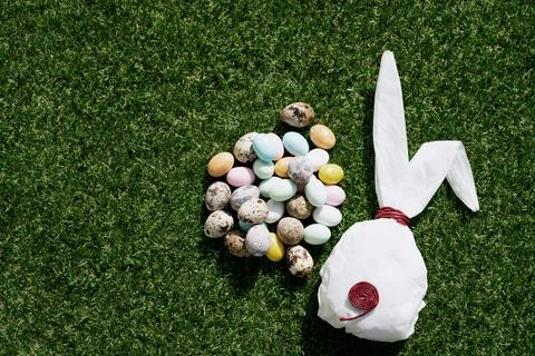 Chocolate Easter eggs glazed with pastel coloring and quail eggs over green g Stock Photos