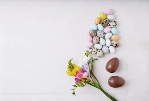 Chocolate Easter eggs glazed with pastel coloring and quail eggs over white b Stock Photos