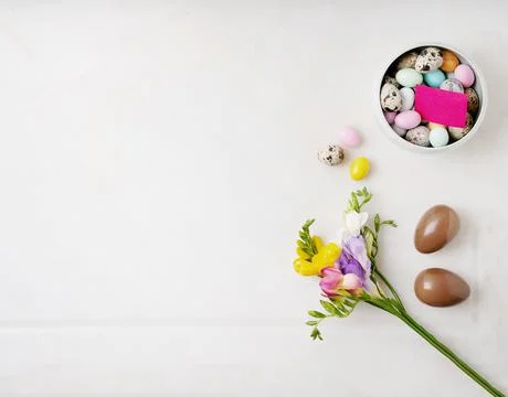 Chocolate Easter eggs glazed with pastel coloring and quail eggs in a bowl ov Stock Photos