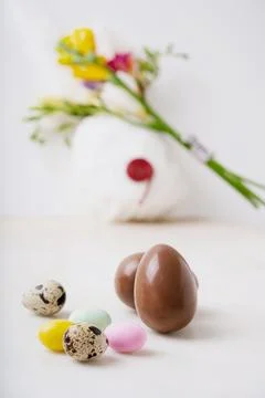 Chocolate Easter eggs glazed with pastel coloring and quail eggs over white b Stock Photos