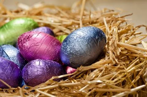 Chocolate easter eggs in a natural straw nest Stock Photos