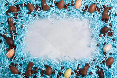 Chocolate easter eggs, rabbits, brown candies on blue packing paper Foto stock