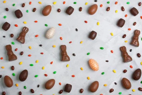 Chocolate easter eggs, rabbits, casks and sweets pattern on concrete backgrou Stock Photos