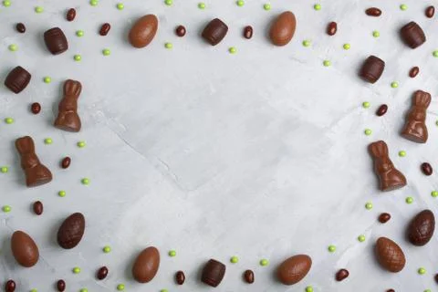 Chocolate easter eggs, rabbits, casks, green sweets on concrete background Stock Photos