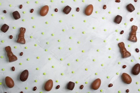 Chocolate easter eggs, rabbits, casks, green sweets on concrete background Stock Photos