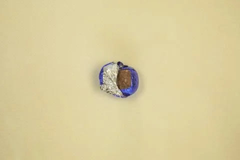 Chocolate Easter eggs wrapped in shiny blue foil yellow background, flat lay top Stock Photos