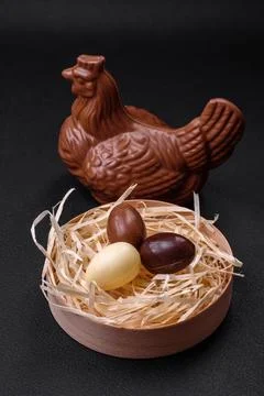 Chocolate Easter hen and eggs in a nest with straw Stock Photos