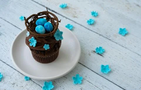 Chocolate easter muffin on plate with chocolate nest and decorative eggs. Spr Stock Photos