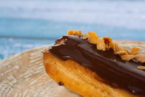 Chocolate eclair with coffee beans on a plate and blue background isolated 스톡 사진