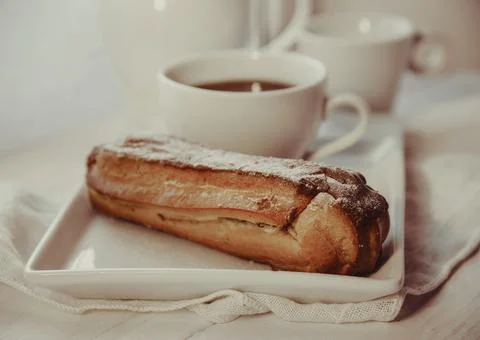 Chocolate eclair on the plate and cup of coffee Stock Photos