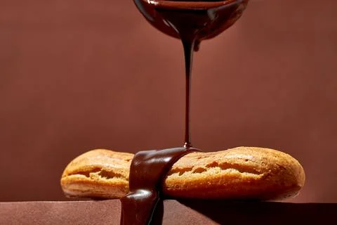 Chocolate eclair is poured with glaze on a brown background. Foto stock