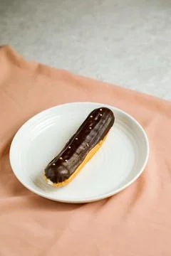 Chocolate Eclair served in plate isolated on napkin side view of cafe baked.. Foto stock