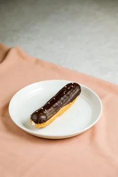Chocolate Eclair served in plate isolated on napkin side view of cafe baked.. Stock Photos