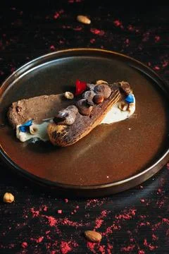 Chocolate eclair with toppings, served on a dark plate Foto stock