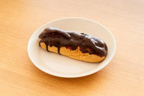 A chocolate eclair on a white dish Stock Photos