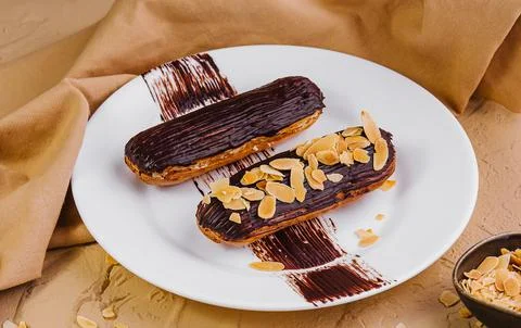 Chocolate eclairs with almonds on plate Stock Photos