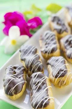 Chocolate eclairs on square white plate, on green background Stock Photos