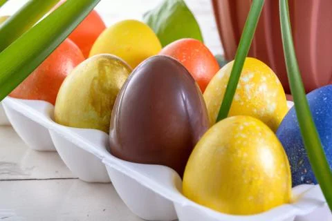 Chocolate egg among colored easter eggs. Stock Photos