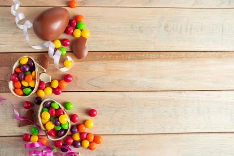 Chocolate eggs for easter holiday. Sweets and ribbons on a wooden background. Stock Photos