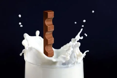Chocolate falling into milk on blue background Stock Photos