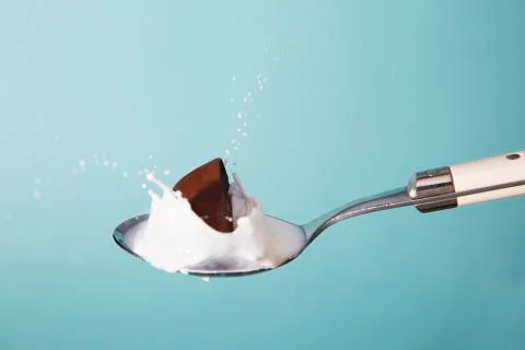 Chocolate falling on a spoon of milk Stock Photos