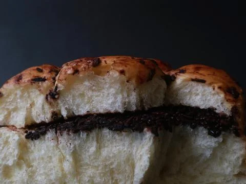 Chocolate-filled bread bun presented against a deep black background Stock Photos