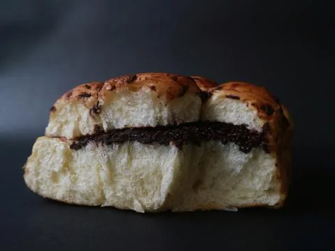 Chocolate-filled bread bun presented against a deep black background Stock Photos
