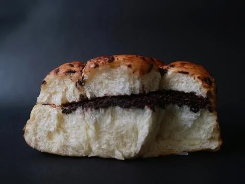 Chocolate-filled bread bun presented against a deep black background Foto stock