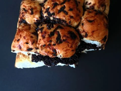 Chocolate-filled bread bun presented against a deep black background Stock Photos