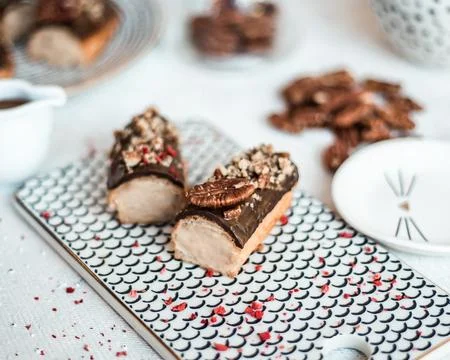 Chocolate Glazed Eclairs with Nuts on Patterned Serving Tray Foto stock