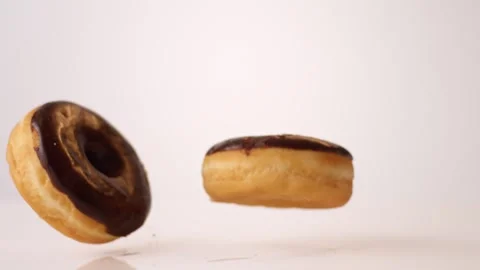 Chocolate iced cake donuts bouncing on white slow motion macro food studio 4K Stock Footage 336705572