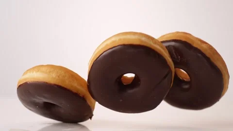 Chocolate iced cake donuts bouncing on white slow motion macro food studio 4K Stock Footage 336706783