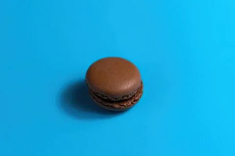 Chocolate macaron cookie on blue background Stock Photos