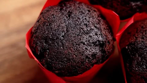 Chocolate muffin in a red paper wrapper on a wooden table Stock Footage 333621482
