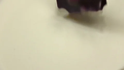 Chocolate with nuts falls into milk. Slow motion, close up Stock Footage 76134054