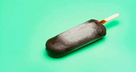 Chocolate outer popsicle melting and reverse on green background time lapse Stock Footage 94579481